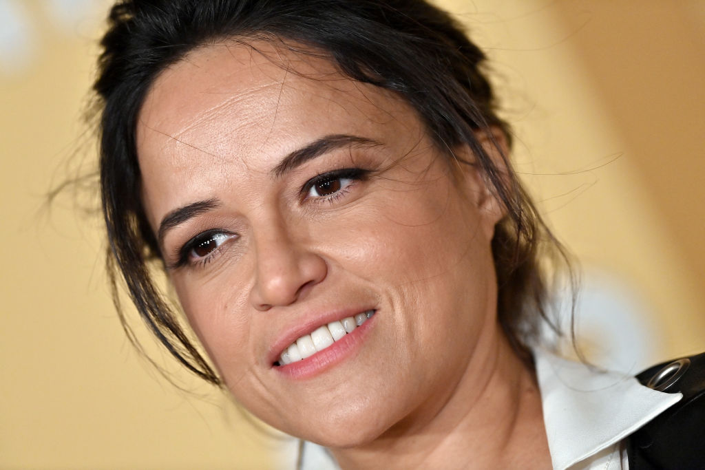Michelle Rodriguez in a white collared shirt with her hair tied up