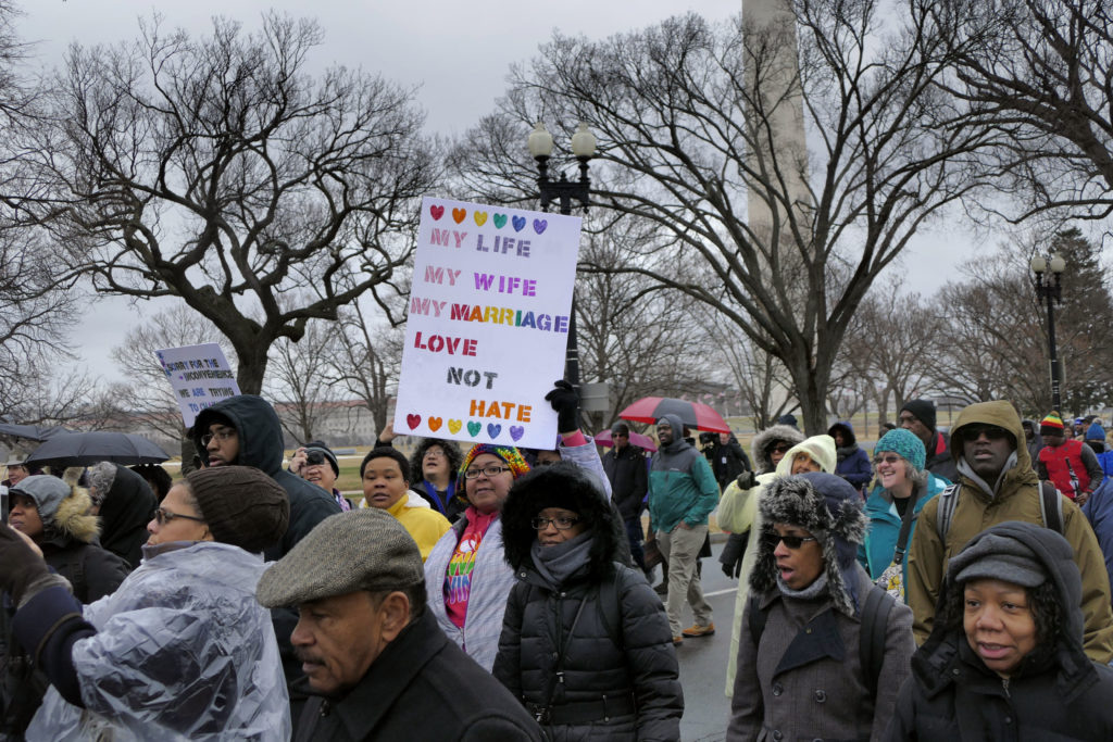 A woman holds a pro-LGBT placard on a Martin Luther King Day march. File photo.
