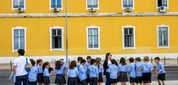 A row of school children in shorts and skirts