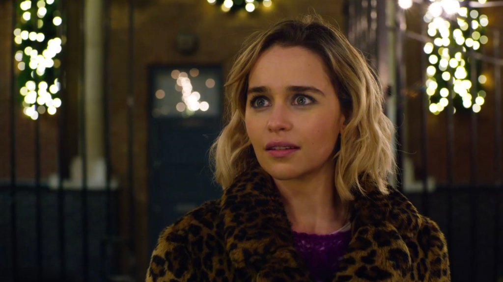 Emilia Clarke looking wide-eyed in a leopard-print coat