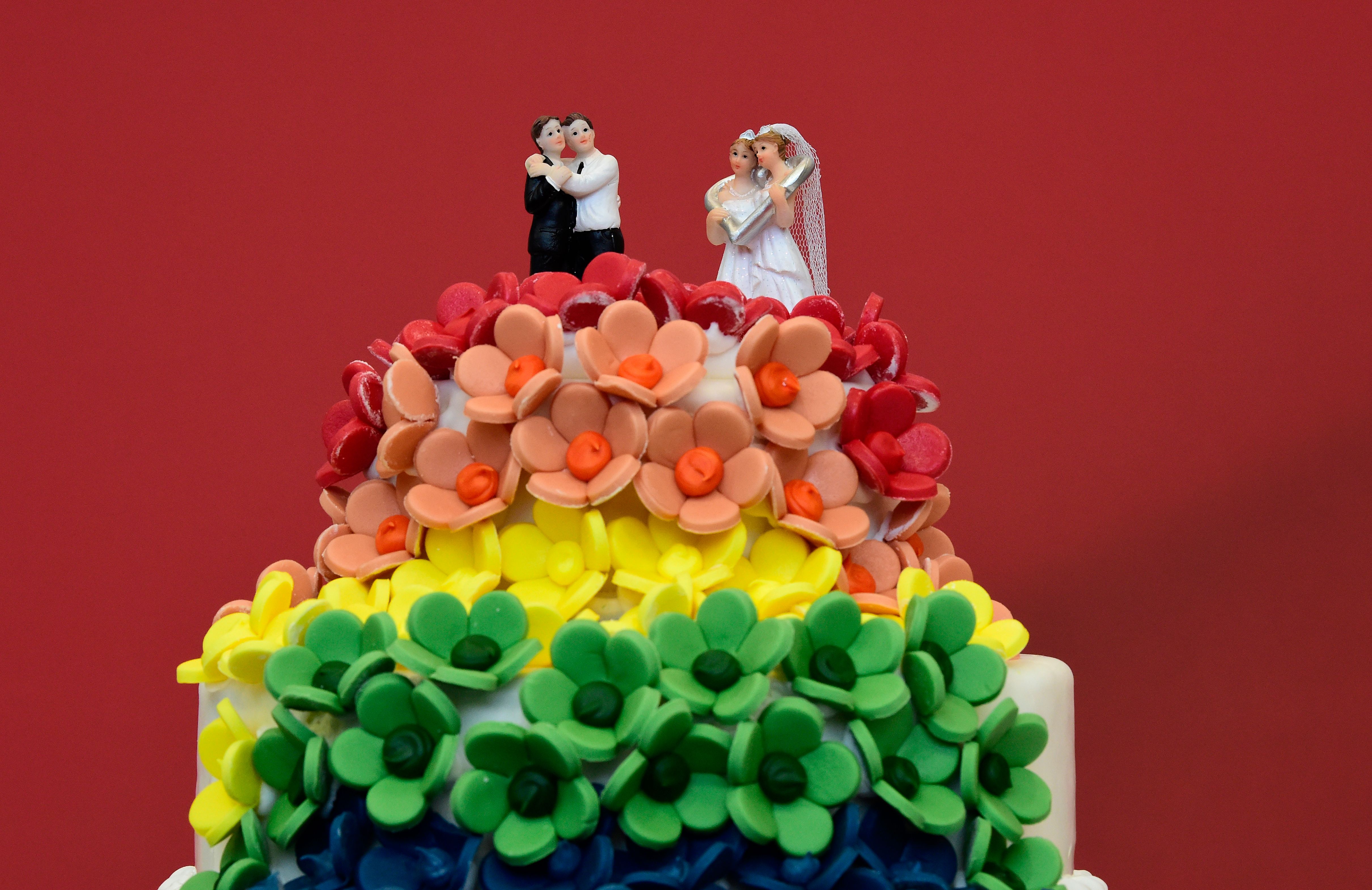 A rainbow wedding cake topped with same-sex couples