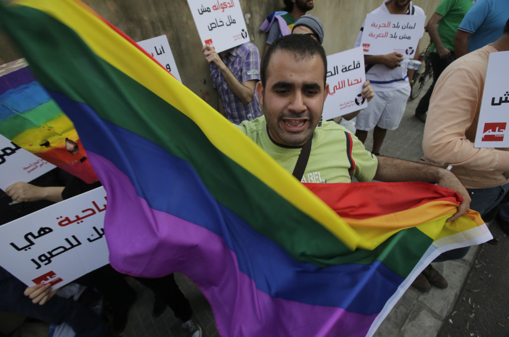 A protester waves the gay pride flag as others hold banners during an anti-homophobia rally in Beirut on April 30, 2013