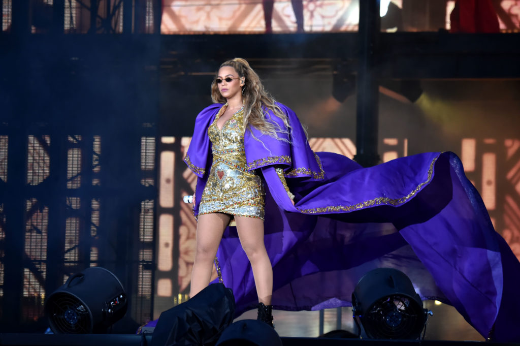 Beyoncé in a gold dress and a long purple cape