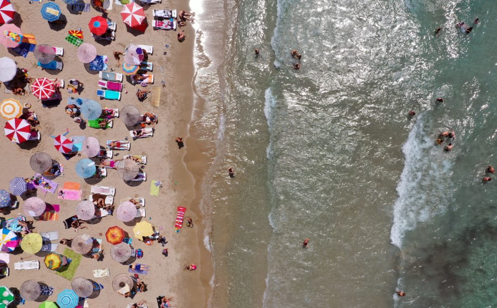 A drone photo shows the aerial view of a beach as people sunbathe under colourful parasols and swim in the sea in Kusadasi district of Aydin, Turkey. (Ferdi Uzun/Anadolu Agency via Getty Images)