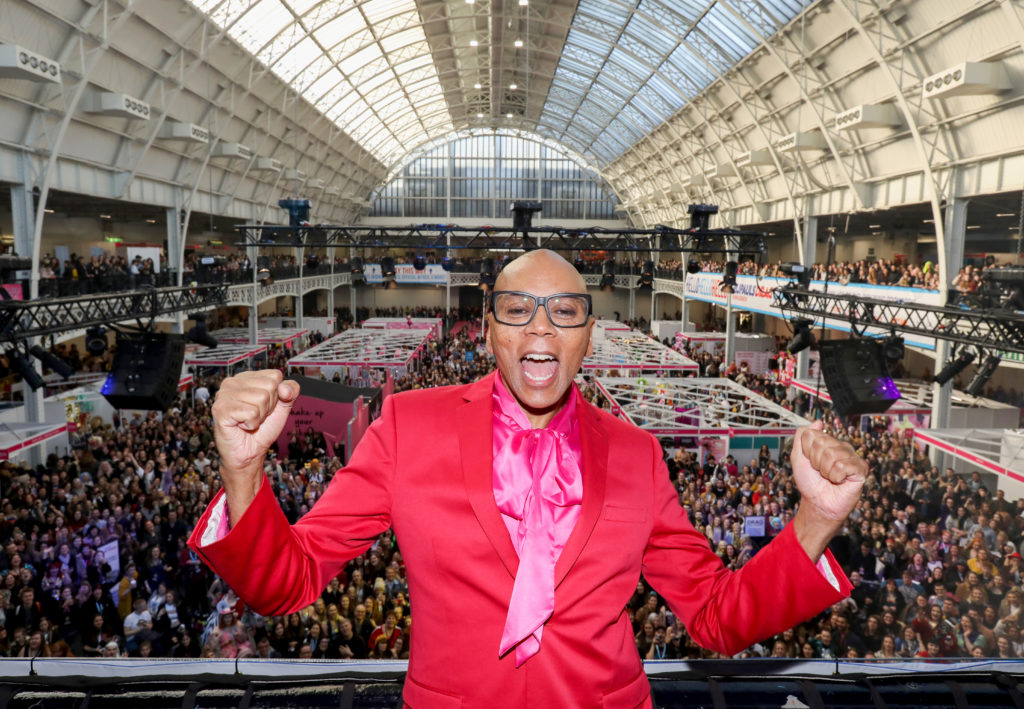 RuPaul standing on a balcony in front of thousands of fans