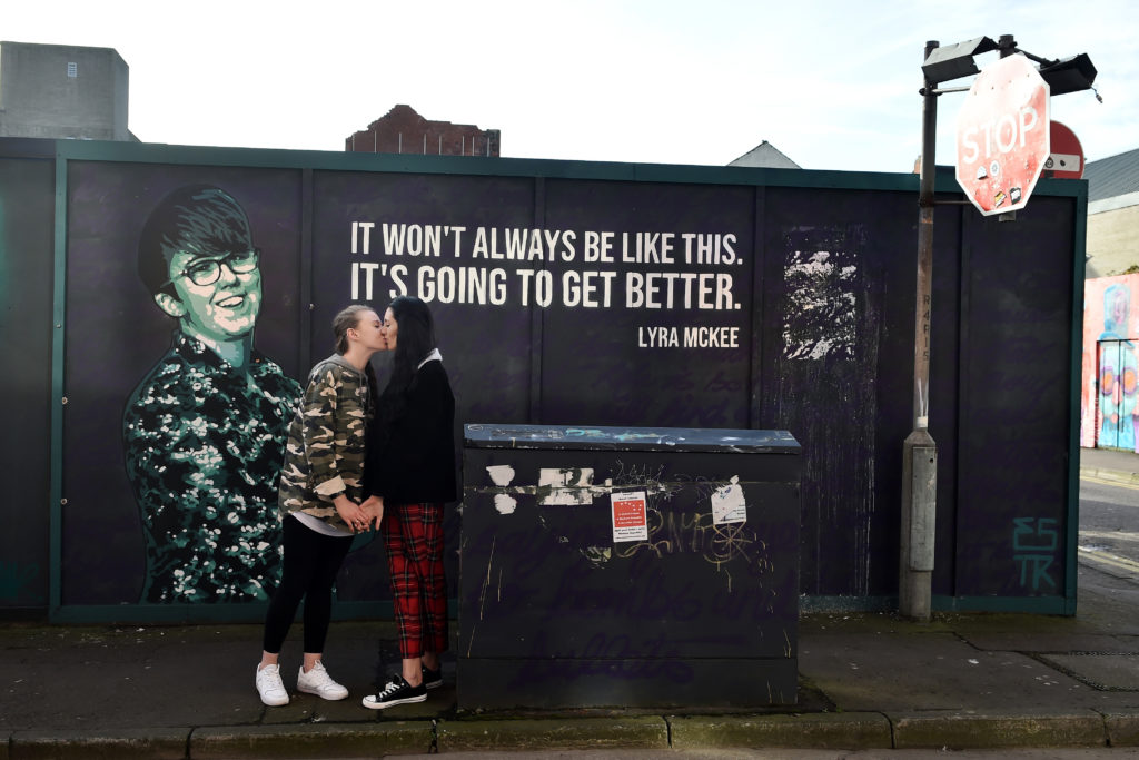 Robyn Peoples (L) and Sharni Edwards, Northern Ireland's first same-sex couple to be legally married, kiss as they pose in front of the Lyra McKee mural. (Charles McQuillan/Getty Images)
