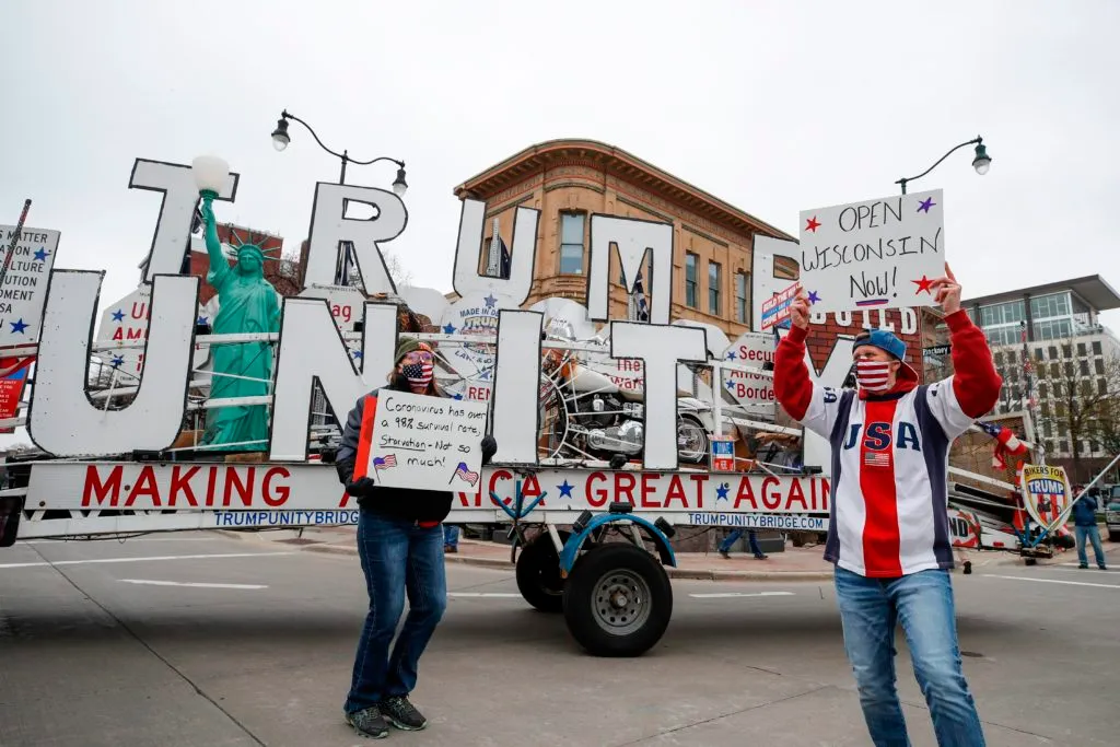 People hold signs during a protest against the coronavirus shutdown in front of State Capitol in Madison, Wisconsin, on April 24 2020. (KAMIL KRZACZYNSKI/AFP via Getty Images)