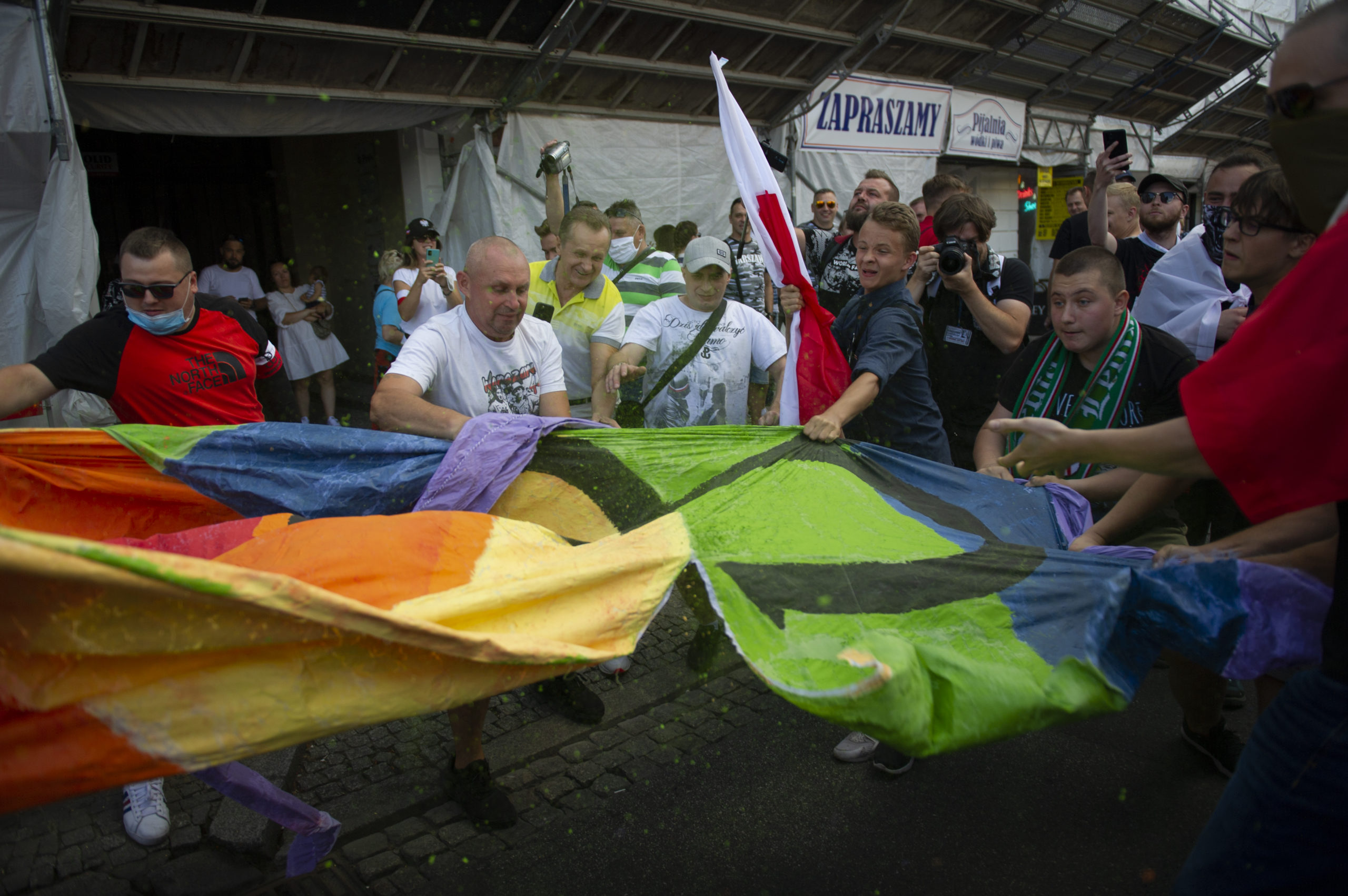 Demonstrators tear a rainbow flag apart during the 76th Warsaw uprising anniversary 