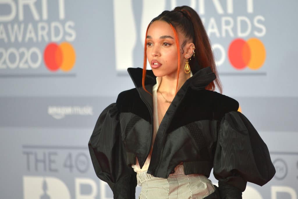 FKA Twigs on the BRITs red carpet in a voluminous cropped jacket, her hair highlighted red in a ponytail with a long fringe