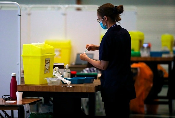 A nurse carries a syringe full of the coronavirus vaccine in a make-shift NHS vaccine centre