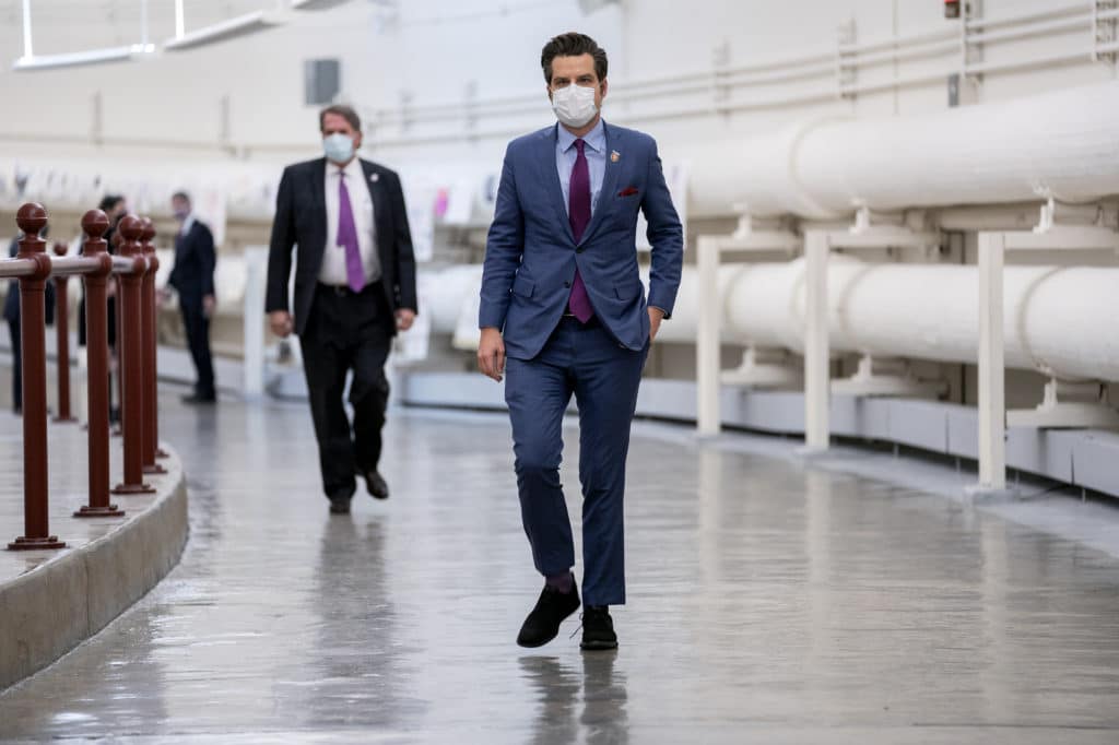 Matt Gaetz in a suit wears a protective mask while walking through the Canon Tunnel 