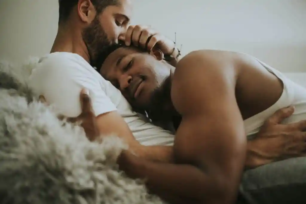 Gay couple cuddling in bed