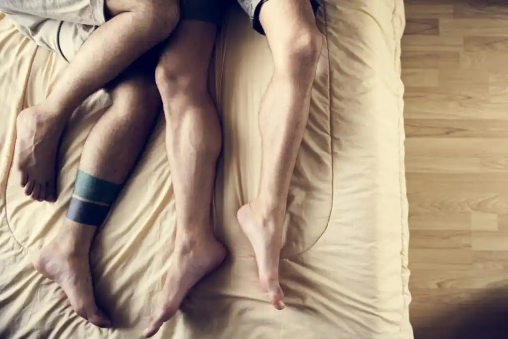 Two men lying in beg, their legs tangled