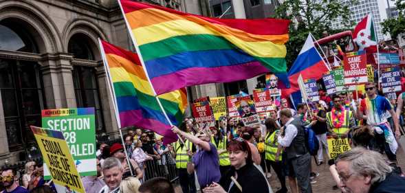 Thousands of members of the LGBTQ community march in the Birmingham Pride parade, holding rainbow flags and signs