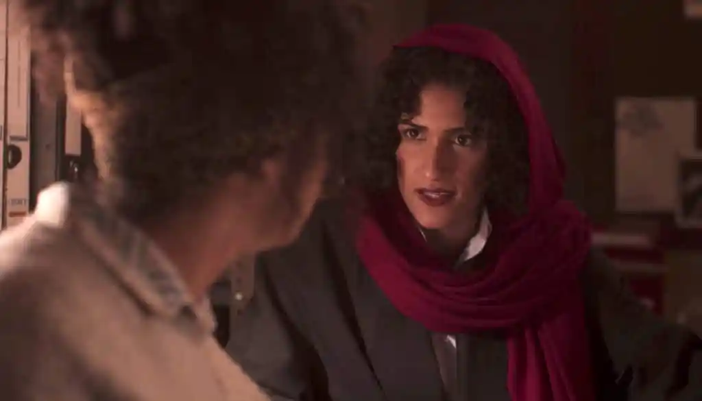 Lizbeth, in a dark suit and read headscarf, deep in conversation with Jill