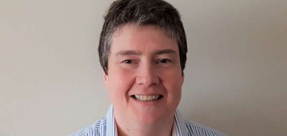 Census director Nicola Tyson-Payne smiling in a blue striped shirt, standing against a white wall