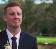 Liam Cooper smirks in a suit against a wooded backdrop