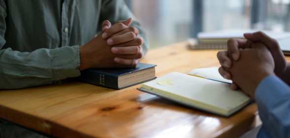 Two people pray with Bibles