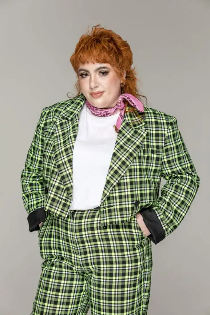 Alex, a woman wearing a green checkered suit with pink hair