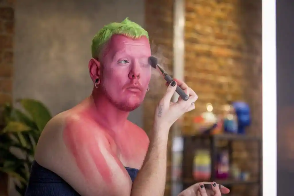 Jack, a white person, painting their face and neck bright pink