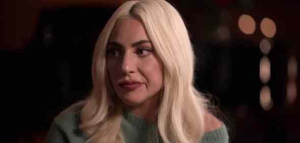 Lady Gaga emotionally looks to the side in a green jumper