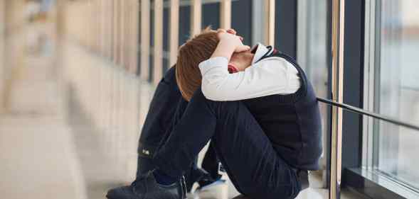 Boy in uniform sitting alone with feeling sad at school. Conception of harassment.