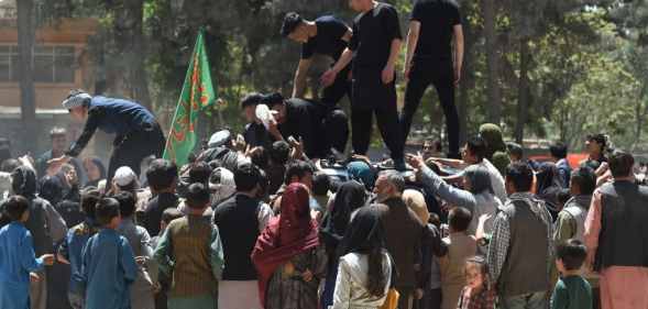 Internally displaced Afghan people, who fled from the northern province due to battle between Taliban and Afghan security forces, gather to receive free food being distributed by Shiite men at Shahr-e-Naw Park in Kabul on August 13, 2021.