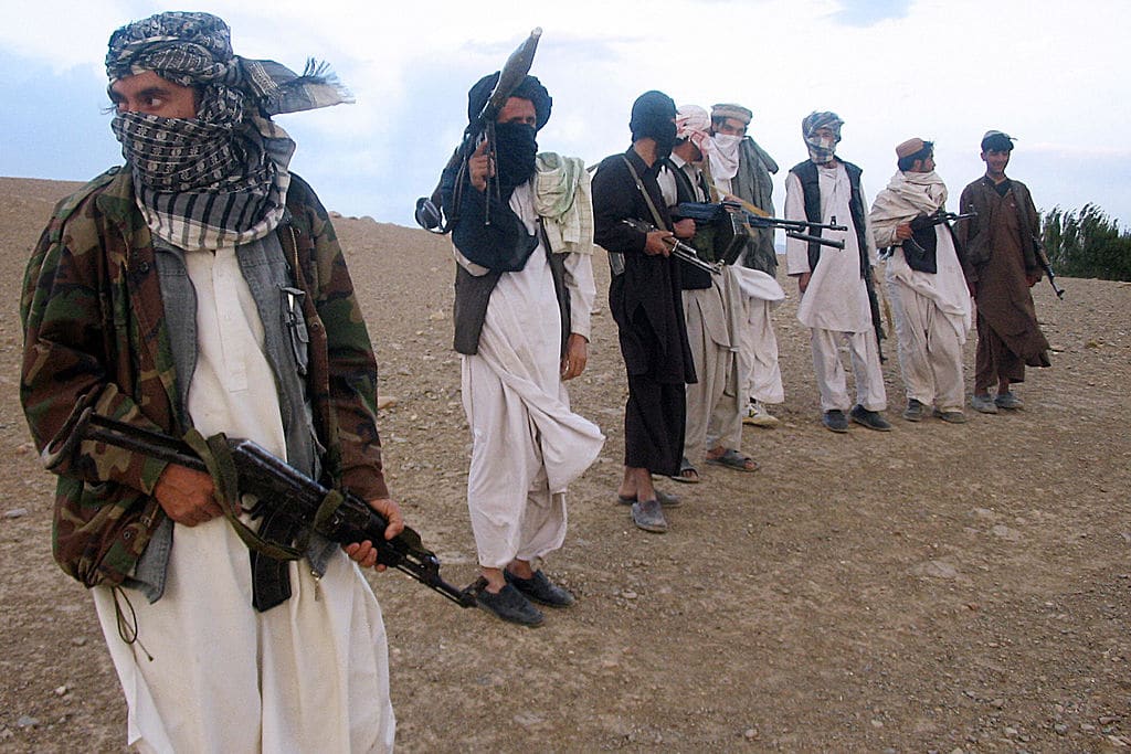 Members of the Taliban stand holding weapons