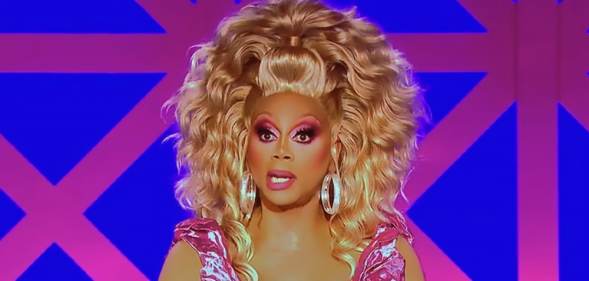 RuPaul in full drag, wearing a pink dress and blonde wig