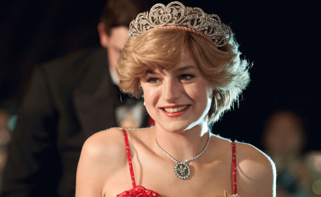 Emma Corrin as PRincess Diana in a red strappy dress, bouffant hair and tiara