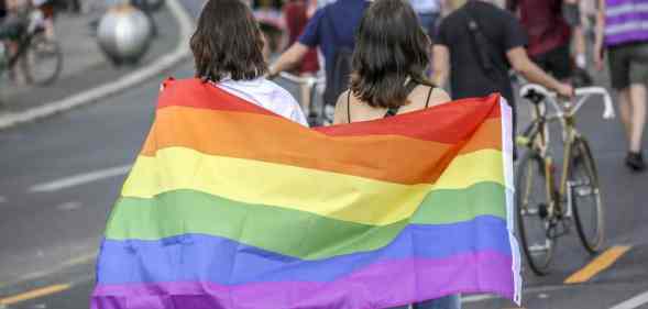 Two women hold the rainbow pride flag as they take part in the Queerschutz Now march in Berlin, Germany