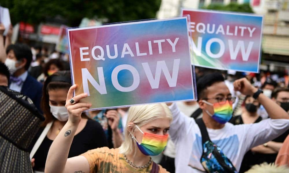 People hold up signs reading 'equality now' during a rally organised by an activist group in support of LGBT+ legislation in Shibuya district of Tokyo, Japan