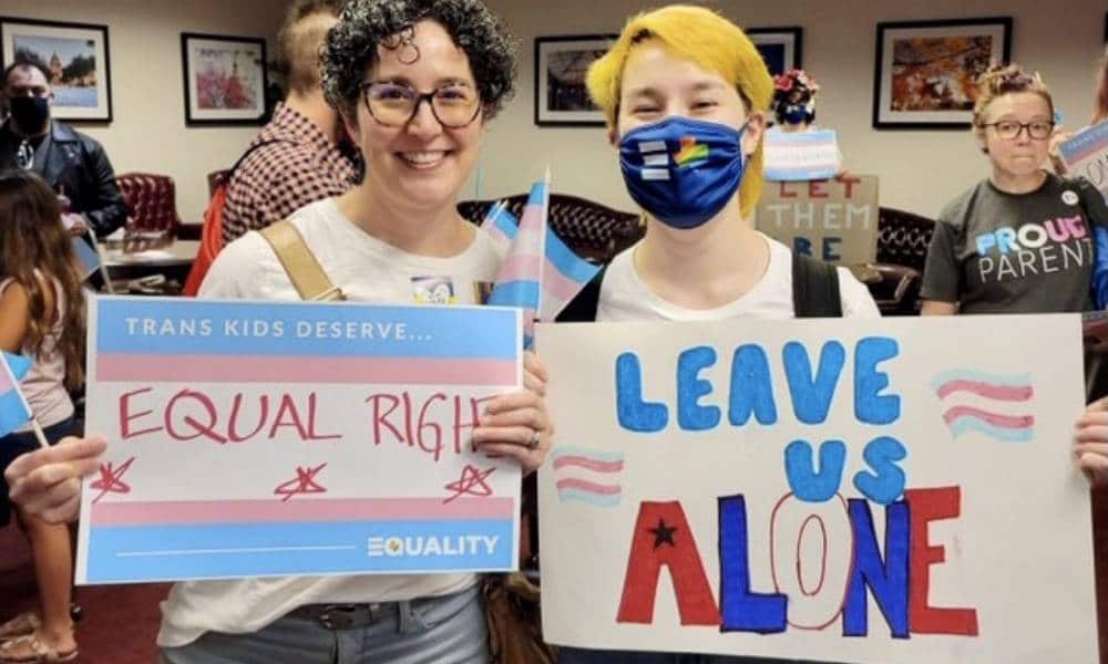 Mandy Giles and Indigo attend a trans rights protest in Texas. Mandy holds up a sign calling for equal rights for trans people while Indigo holds up a right that reads 'leave us alone'