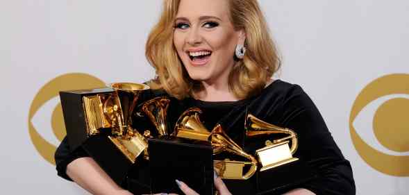 Adele holding an armful of Grammys