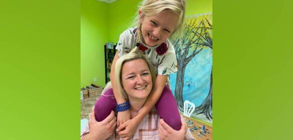 Sunny Bryant smiles and sits on the shoulders of her mum, Bekah