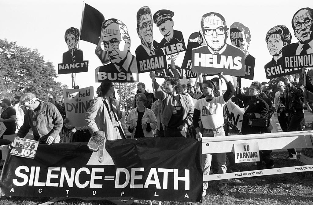 Members of AIDS activist group ACT UP hold up signs of George W. Bush, Ronald Reagan, Nancy Reagan, Jesse Helms and other with the word "Guilty" stamped on their foreheads on October 11, 1988