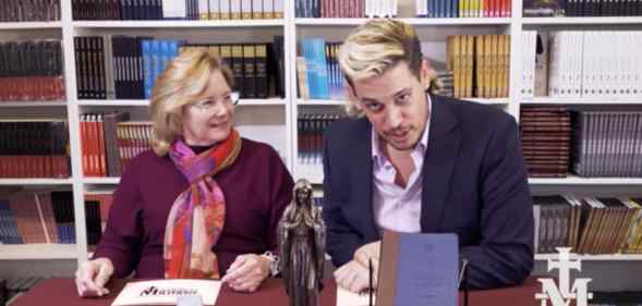 Milo Yiannopolous and a woman sat at a desk with a Virgin mary statue