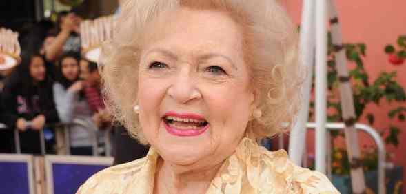 Betty White smiles at the camera while wearing a light yellow patterned top