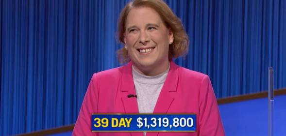 Jeopardy! champion Amy Schneider wears a pink top and darker pink jacket as she smiles after she wins her 39th consecutive game