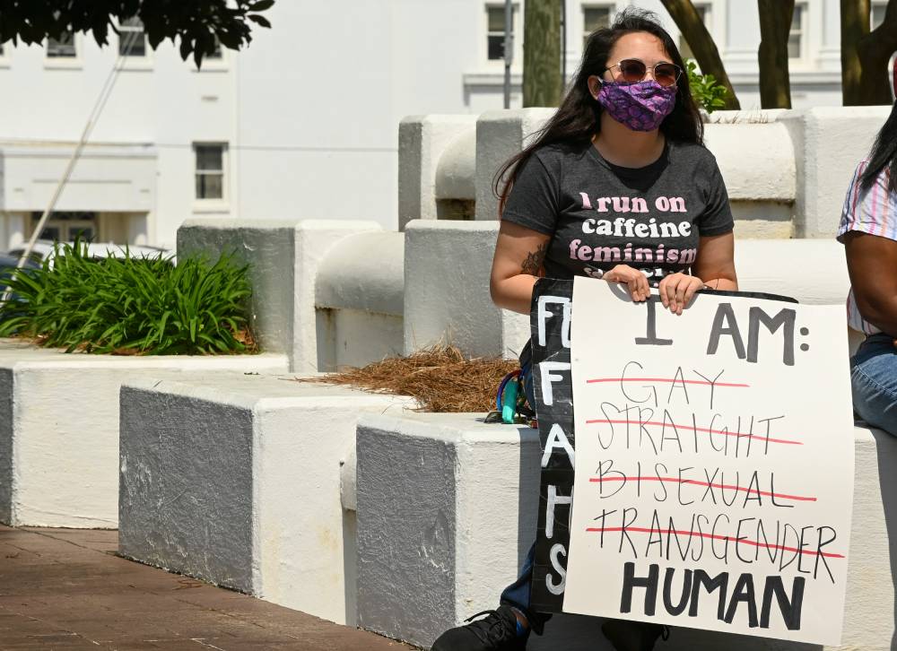 A person holds up a sign at a protest against anti-trans legislation in Alabama that reads "I am human" with the words "gay", "straight", "bisexual" and "transgender" crossed out