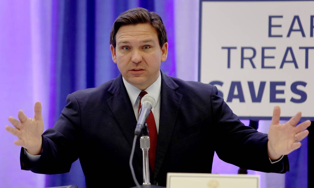 Florida governor Ron DeSantis holds up his arms during a press conference