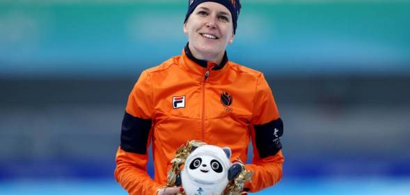 Ireen Wüst, an Olympic speed skater, poses with a panda mascot for the Beijing Olympics while wearing an orange jacket