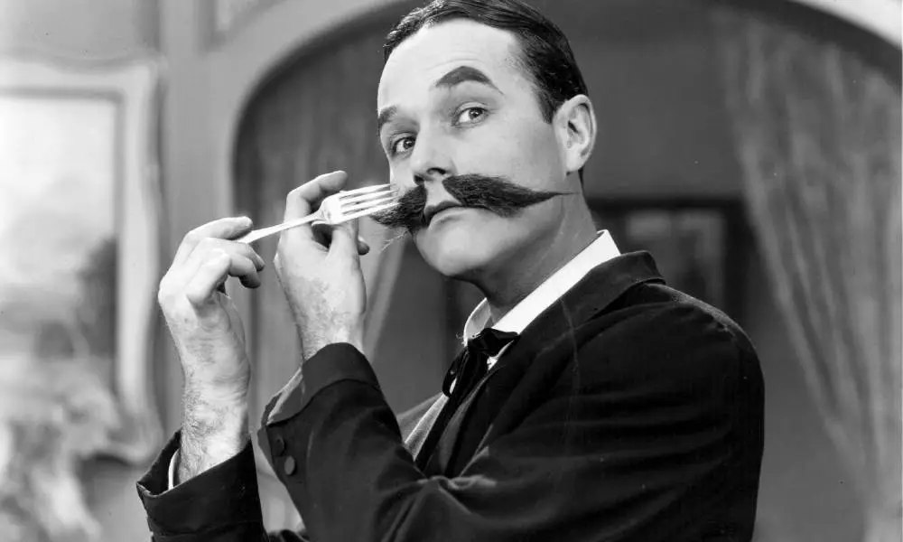 William Haines, a silent film star, combs his moustache with a fork