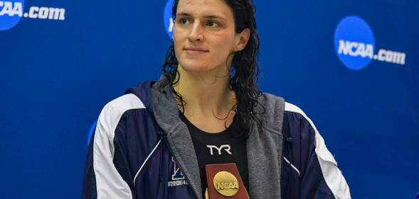 University of Pennsylvania swimmer Lia Thomas holds an NCAA trophy while she looks off to the side