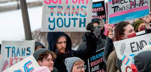 Person holds up a sign that reads "support trans youth" amid a rally in support of trans kids across the USA