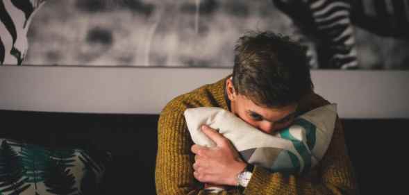 A man hugs a pillow in a bedroom