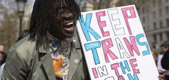 A demonstrator holds a placard demanding a ban on trans conversion therapy at a protest opposite Downing Street