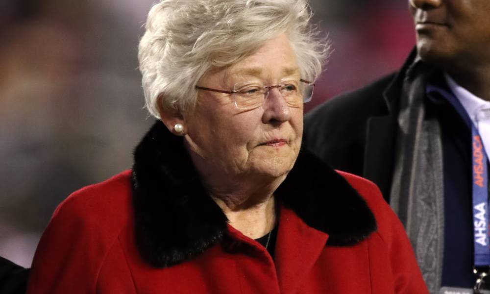 Republican governor of Alabama Kay Ivey wears a red coat with a black fuzzy collar