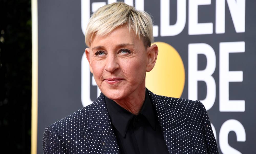 Ellen DeGeneres wears a black shirt, dark jacket which is decorated with rhinestones as she stares off camera