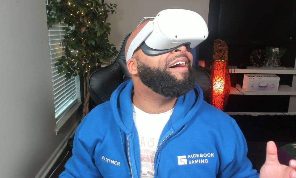 Michael Reynolds, a Black LGBTQ+ gamer, wears a gaming headset while dressed in a white t-shirt and blue zip up sweatshirt